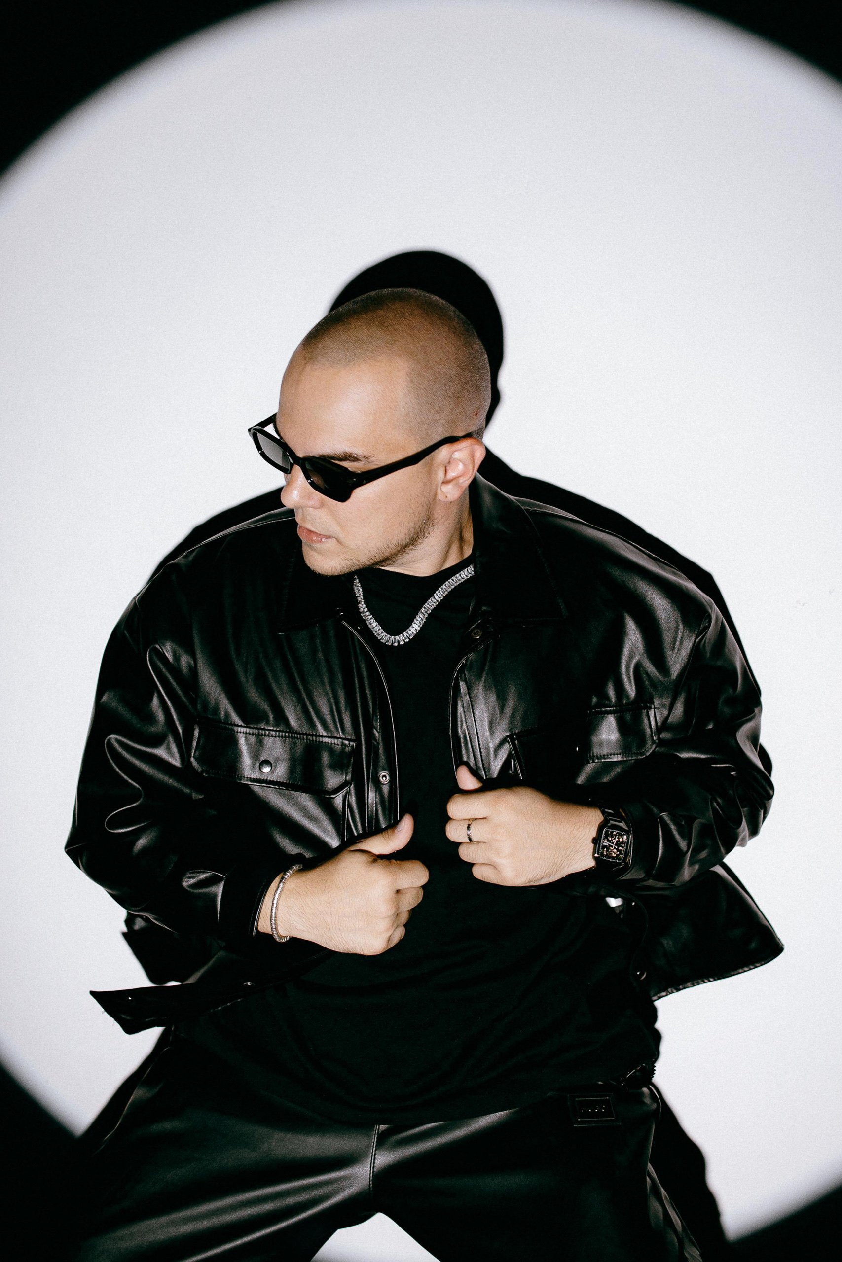 BYOR in a leather jacket inside a white spotlight